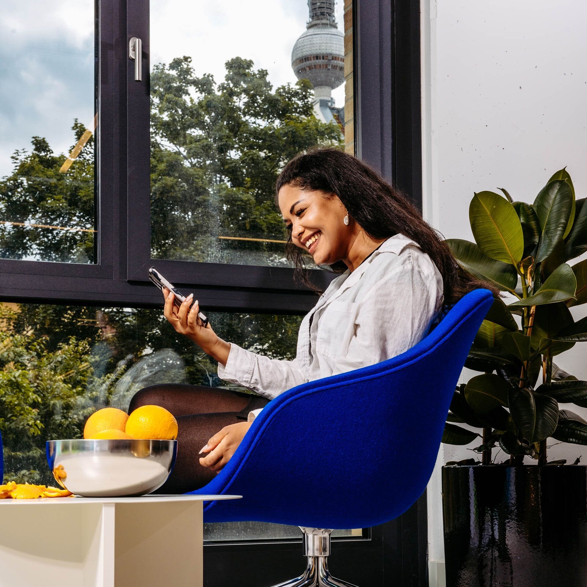 Metacore sitting in a chair, smiling at a phone, in the Berlin office