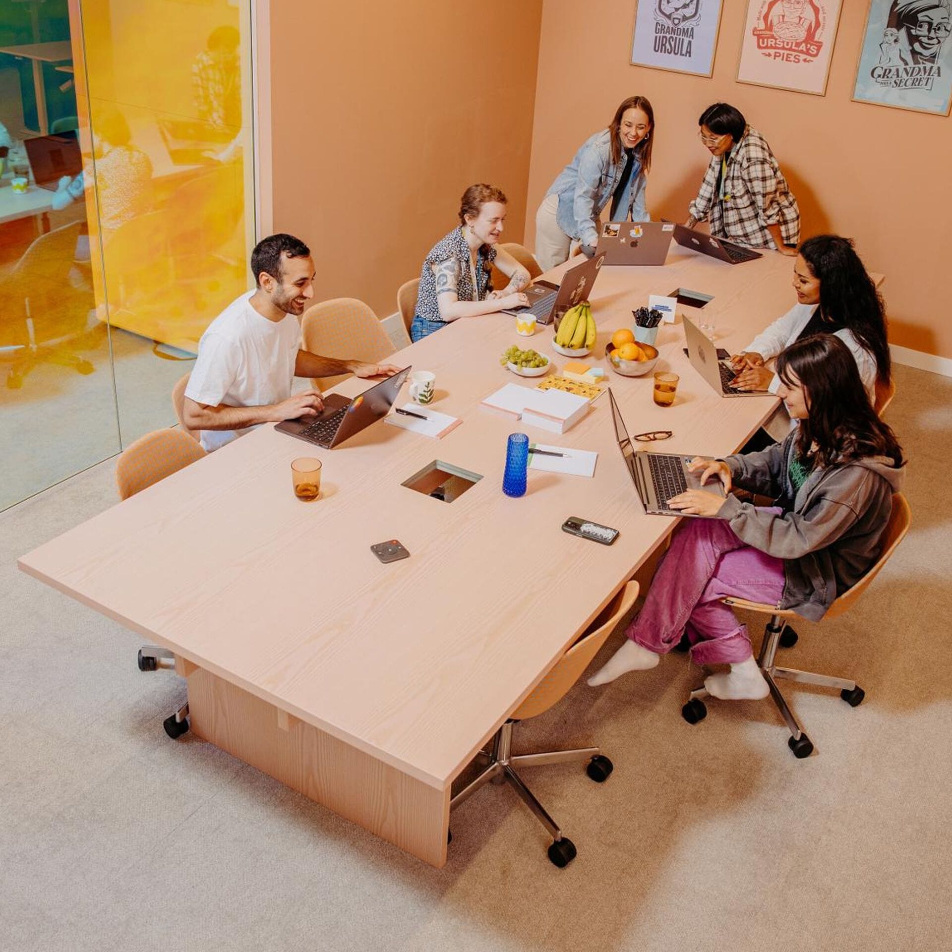 Six Metacoreans sitting around a meeting desk with their laptops