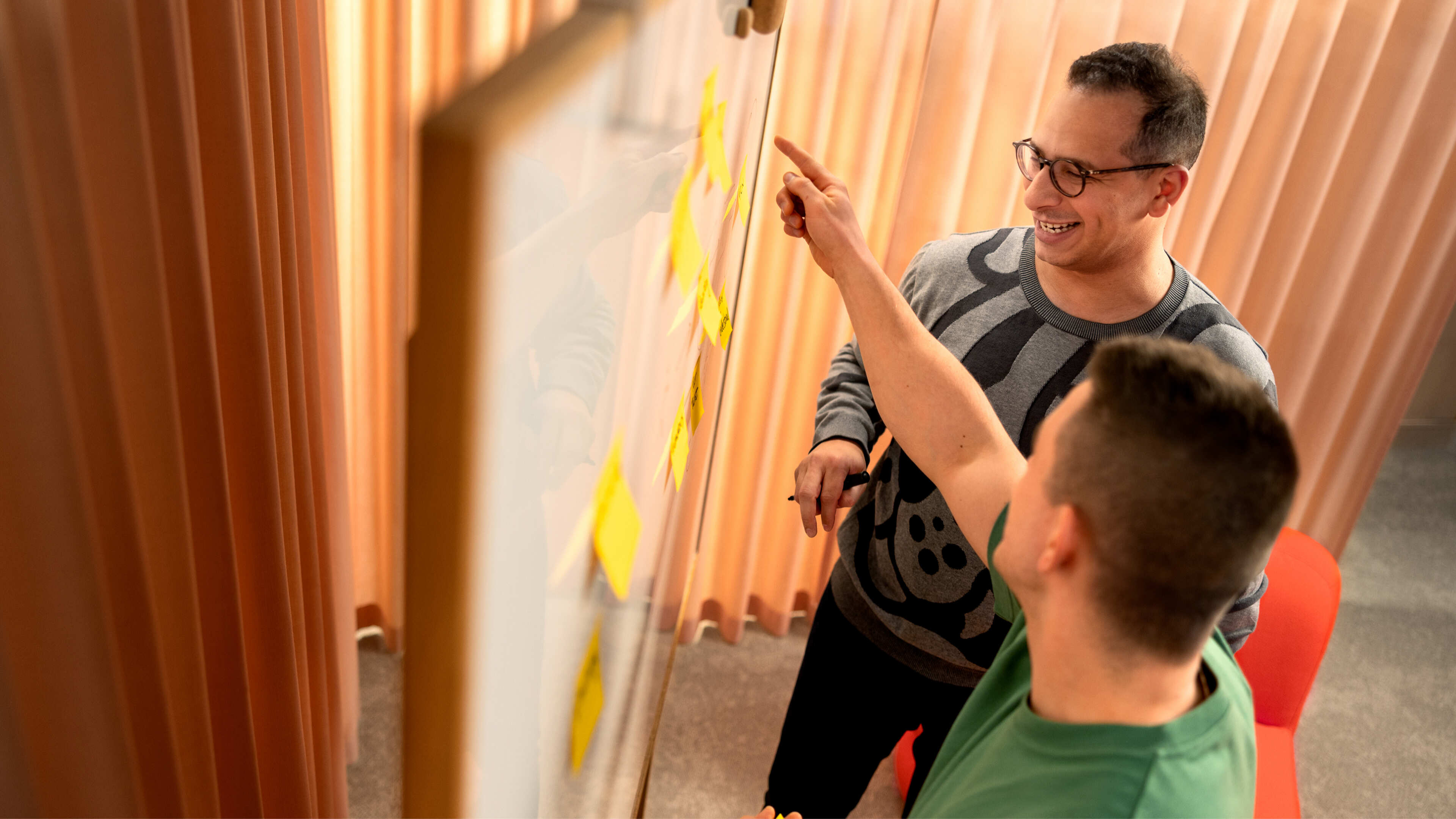 Two people collaborating in front of a whiteboard